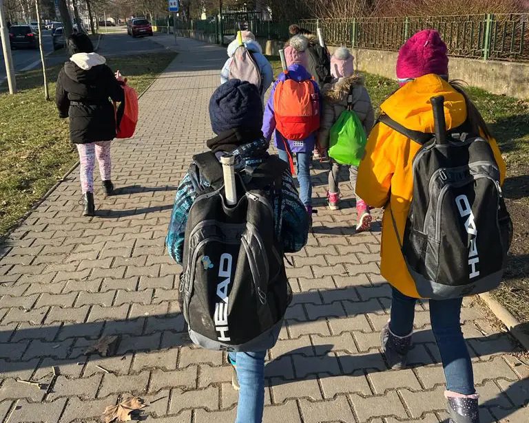 Děti s tenisovými batohy cestou na trénink